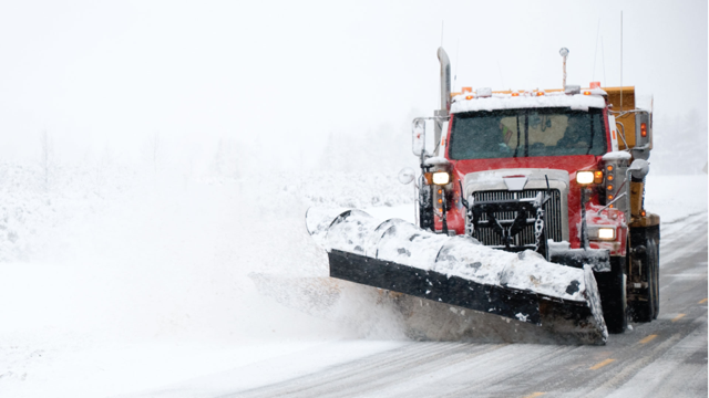 image of snow plow clearing a road in a winter storm